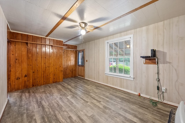 empty room featuring wood walls, hardwood / wood-style floors, and ceiling fan