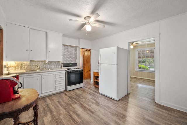 kitchen with light hardwood / wood-style flooring, ceiling fan, white appliances, and white cabinets