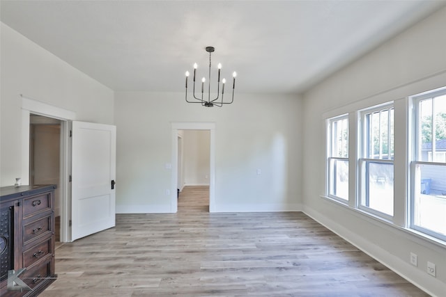 unfurnished dining area with a notable chandelier and light hardwood / wood-style flooring