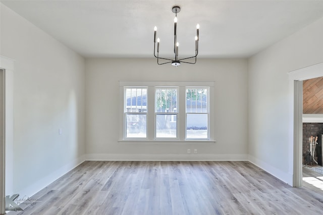 unfurnished dining area with light wood-type flooring and an inviting chandelier