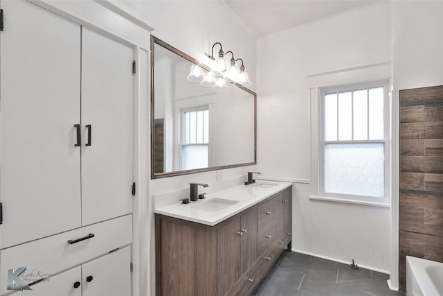 bathroom with an inviting chandelier, a wealth of natural light, double sink vanity, and tile patterned flooring