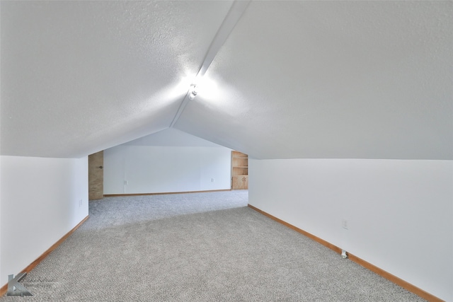 bonus room with vaulted ceiling, light colored carpet, and a textured ceiling