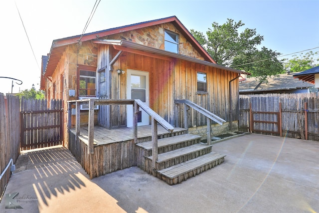 rear view of house featuring a wooden deck and a patio