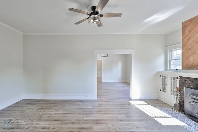 unfurnished living room with light hardwood / wood-style floors, ornamental molding, a fireplace, and ceiling fan