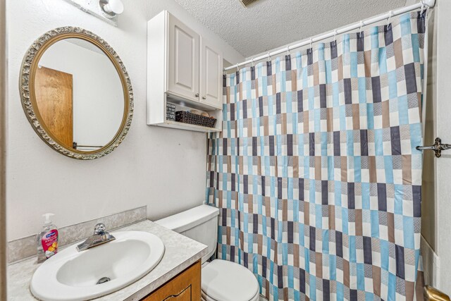 bathroom with vanity, toilet, and a textured ceiling