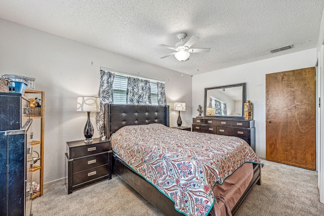 bedroom featuring light carpet, a textured ceiling, and ceiling fan