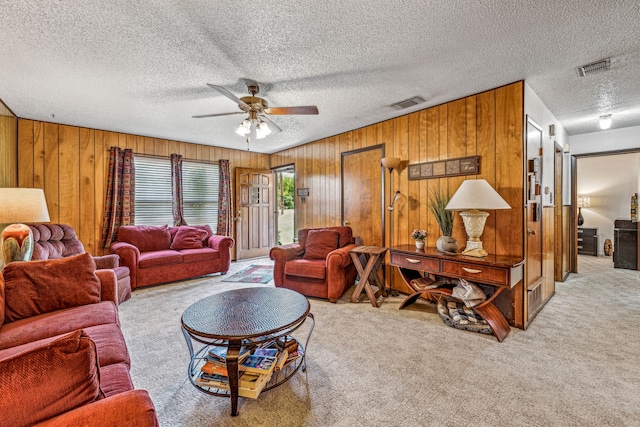 living room featuring light carpet, wood walls, a textured ceiling, and ceiling fan