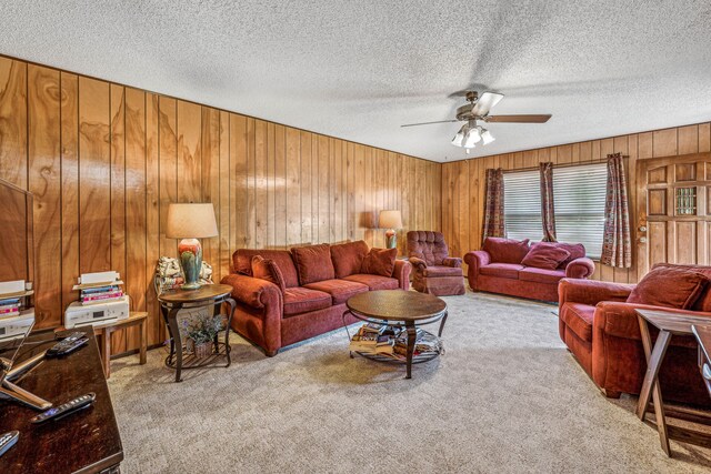 carpeted living room with ceiling fan, a textured ceiling, and wooden walls