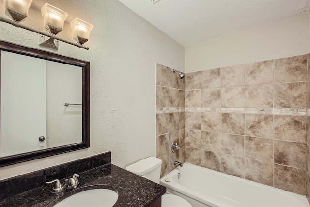 full bathroom with tiled shower / bath, vanity, and toilet