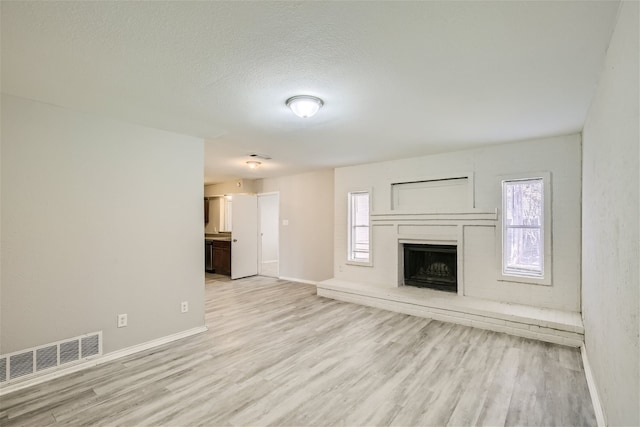 unfurnished living room featuring a textured ceiling and light hardwood / wood-style flooring