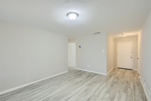 spare room featuring a textured ceiling and light hardwood / wood-style flooring