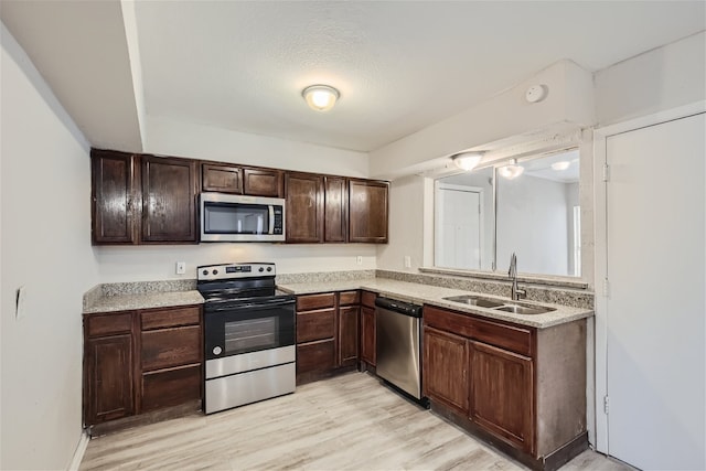 kitchen with light hardwood / wood-style flooring, sink, dark brown cabinets, and stainless steel appliances