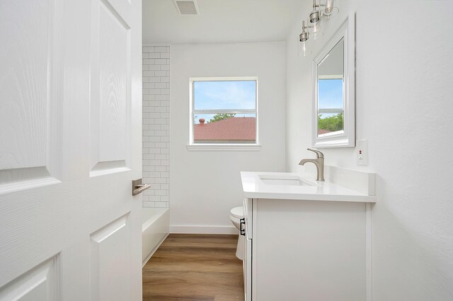 full bathroom featuring hardwood / wood-style floors, tiled shower / bath combo, toilet, and vanity