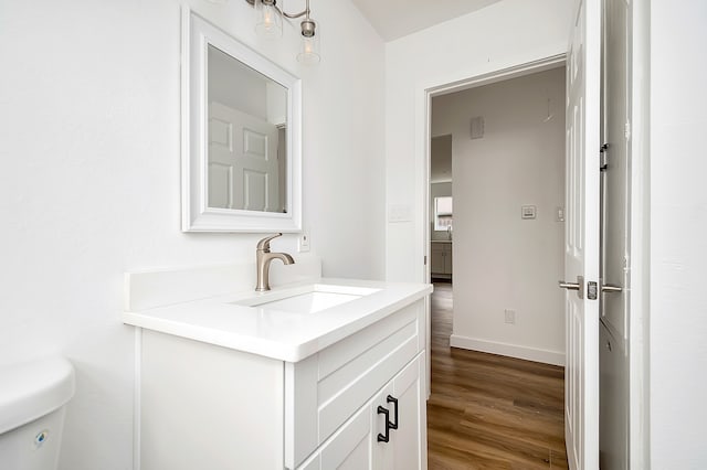 bathroom with toilet, hardwood / wood-style floors, and vanity