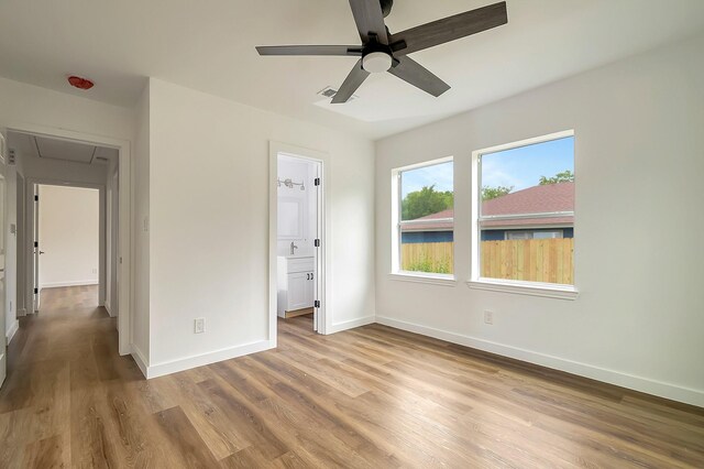 unfurnished bedroom with ensuite bathroom, wood-type flooring, and ceiling fan