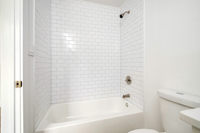 bathroom featuring tiled shower / bath and toilet