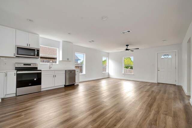 kitchen with appliances with stainless steel finishes, hardwood / wood-style flooring, white cabinets, sink, and ceiling fan