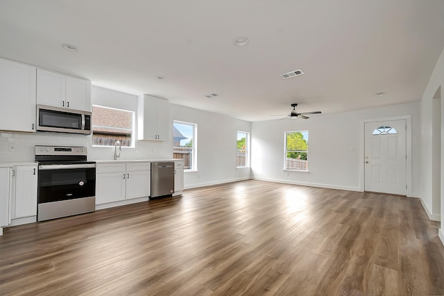 kitchen featuring white cabinetry, hardwood / wood-style floors, tasteful backsplash, and stainless steel appliances