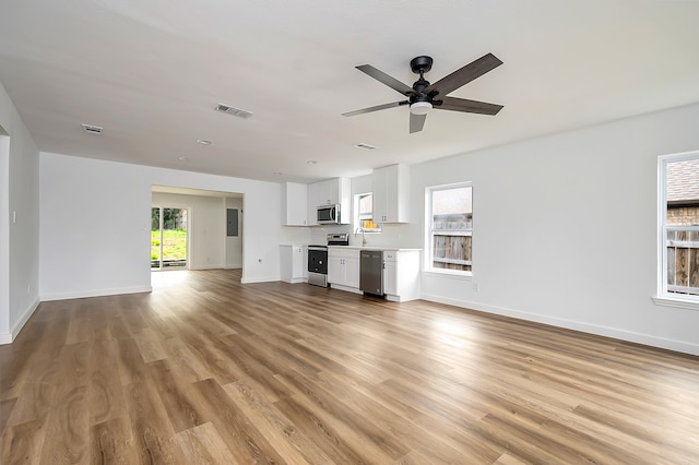 unfurnished living room featuring sink, light hardwood / wood-style flooring, and ceiling fan