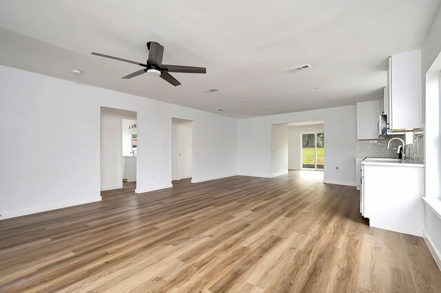 unfurnished living room featuring sink, ceiling fan, and light hardwood / wood-style floors