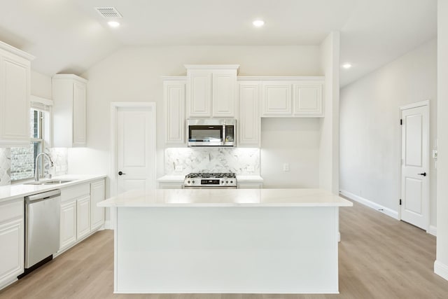 kitchen featuring stainless steel appliances, a kitchen island, sink, and white cabinets