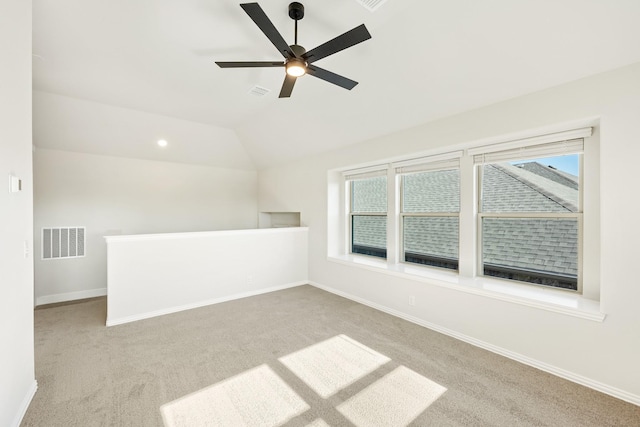 carpeted spare room featuring ceiling fan and vaulted ceiling