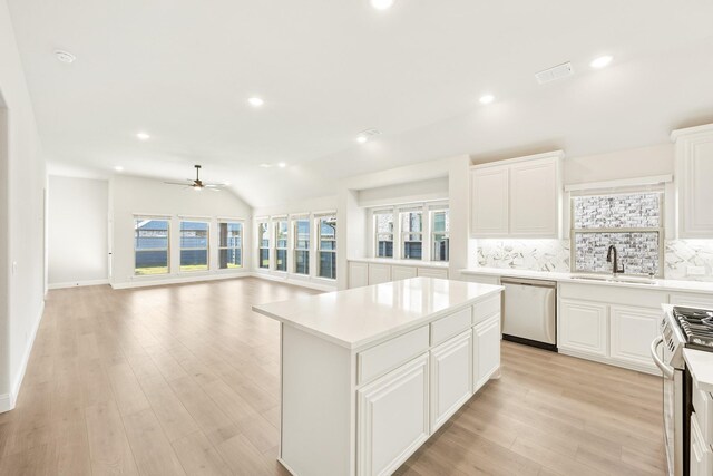 kitchen with sink, a center island, backsplash, white cabinets, and appliances with stainless steel finishes