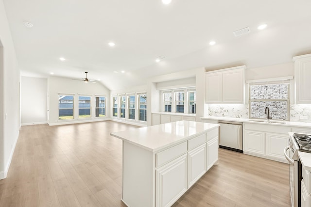 kitchen with sink, backsplash, stainless steel appliances, white cabinets, and a kitchen island