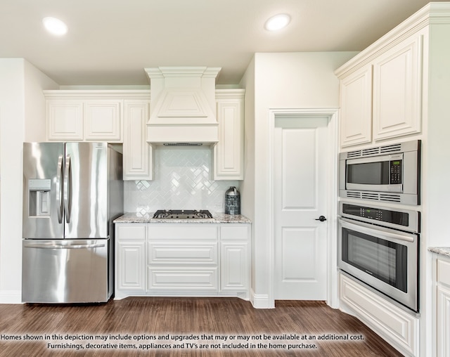 kitchen with backsplash, premium range hood, light stone counters, dark hardwood / wood-style floors, and appliances with stainless steel finishes