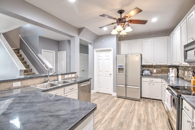 kitchen featuring appliances with stainless steel finishes, tasteful backsplash, sink, light wood-type flooring, and ceiling fan