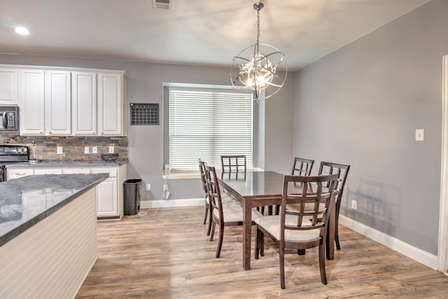 dining space with light hardwood / wood-style flooring and a chandelier