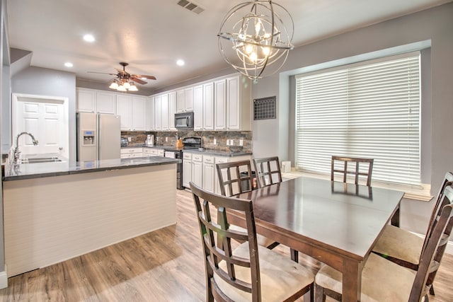 dining space featuring light hardwood / wood-style floors, sink, and ceiling fan with notable chandelier