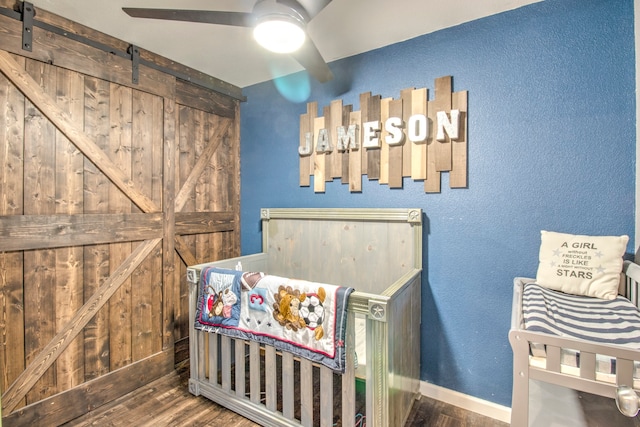 bedroom with ceiling fan, hardwood / wood-style flooring, and a barn door