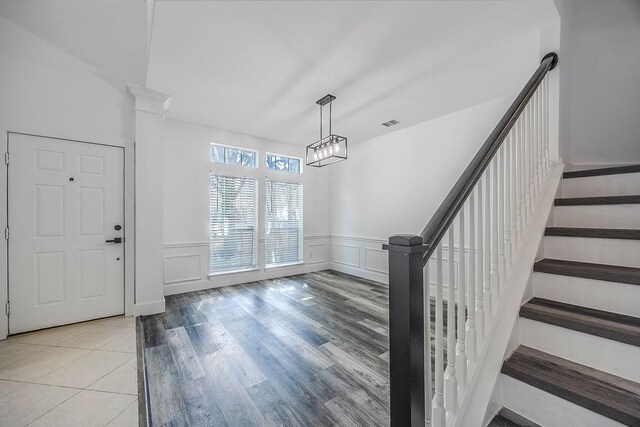 entryway featuring a notable chandelier, decorative columns, and hardwood / wood-style floors