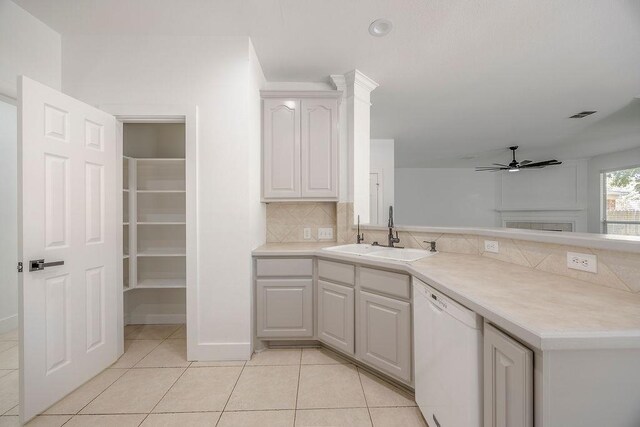 kitchen featuring white dishwasher, ceiling fan, light tile patterned floors, backsplash, and sink