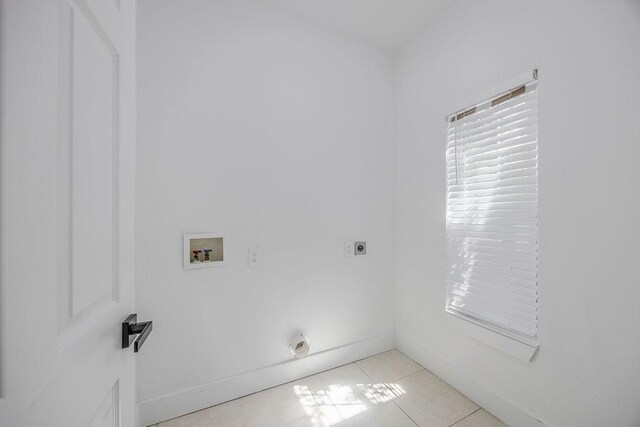 clothes washing area with electric dryer hookup, hookup for a washing machine, and light tile patterned floors