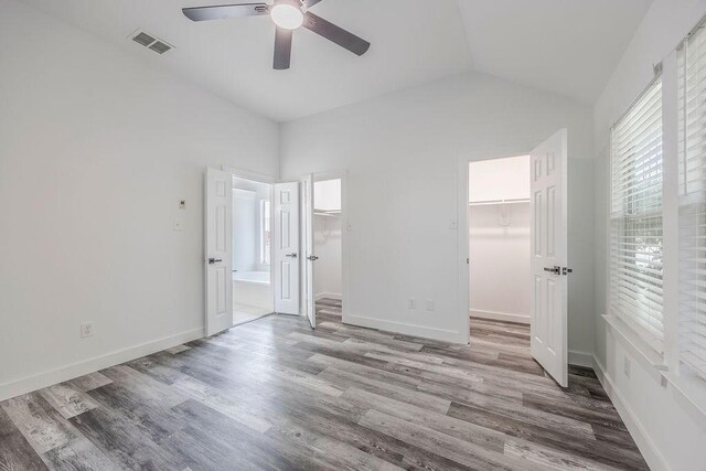 unfurnished bedroom featuring ceiling fan, lofted ceiling, hardwood / wood-style flooring, a spacious closet, and a closet