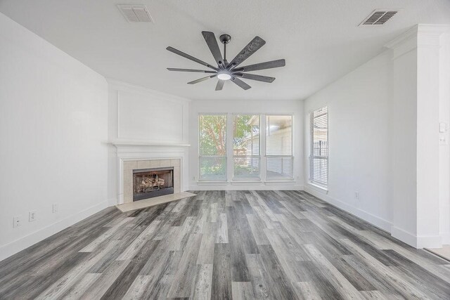 unfurnished living room featuring ceiling fan, wood-type flooring, and a fireplace