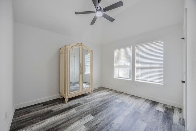 empty room with ceiling fan, vaulted ceiling, and hardwood / wood-style flooring