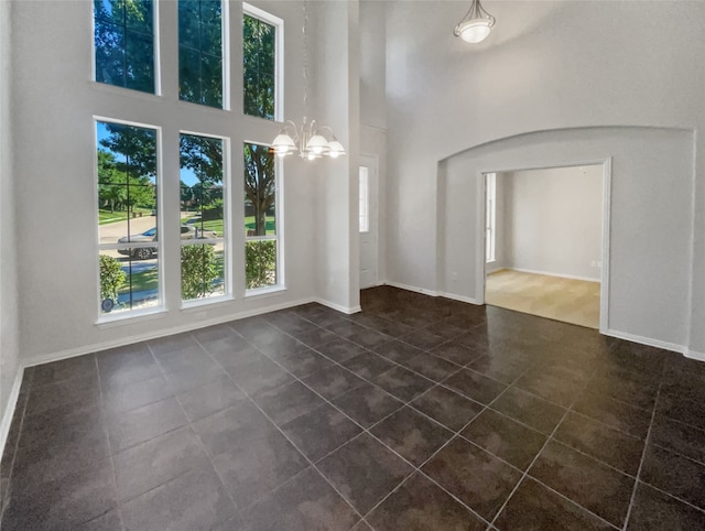 tiled empty room featuring a high ceiling and a chandelier