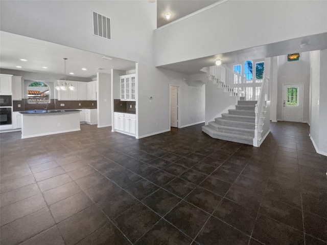 unfurnished living room featuring sink, dark tile patterned floors, and a towering ceiling