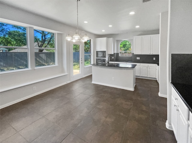 kitchen with white cabinetry, a healthy amount of sunlight, tasteful backsplash, and dark tile patterned flooring