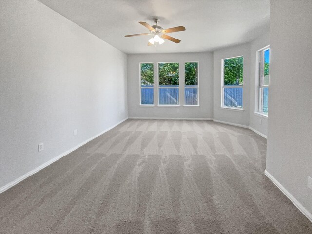 carpeted empty room with ceiling fan and plenty of natural light