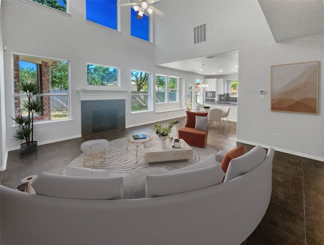 living room featuring ceiling fan, a healthy amount of sunlight, and a towering ceiling