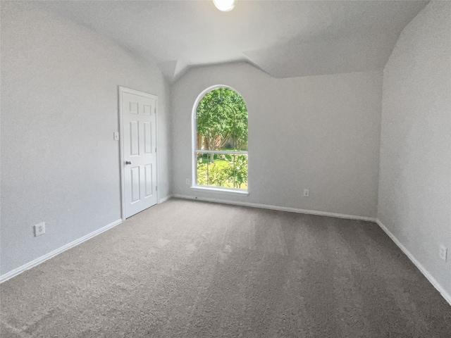 empty room featuring carpet and vaulted ceiling