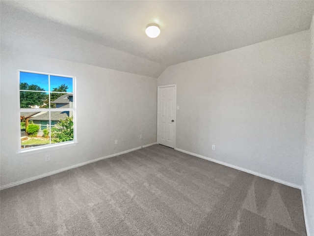 carpeted empty room with vaulted ceiling