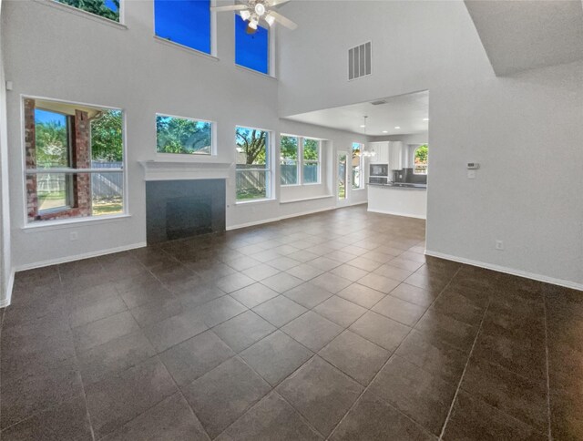 unfurnished living room featuring tile patterned flooring, a towering ceiling, and ceiling fan