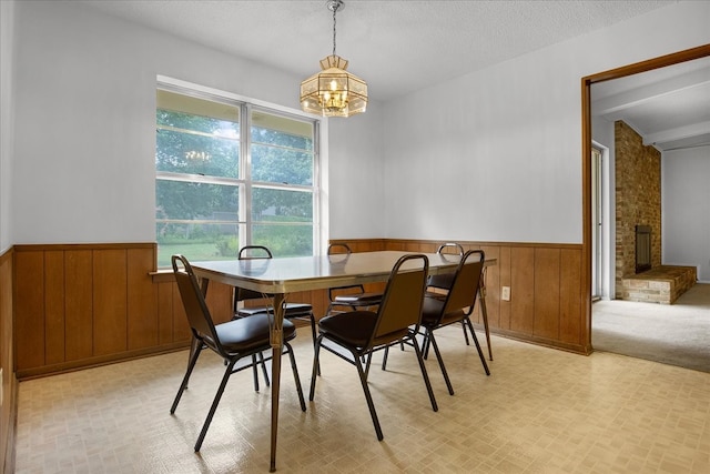 carpeted dining space with a fireplace, a notable chandelier, and a textured ceiling