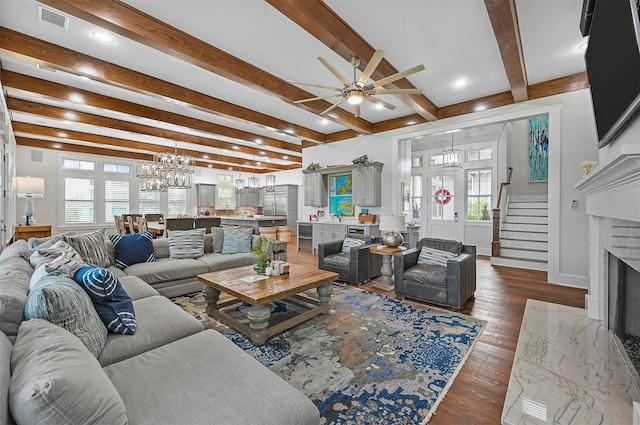 living room with dark wood finished floors, visible vents, a fireplace with flush hearth, beamed ceiling, and stairs