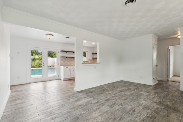 unfurnished living room with french doors, wood-type flooring, and ornamental molding